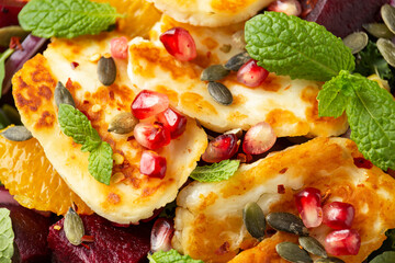 Fried Halloumi Cheese salad with beetroot, orange, pomegranate and pumpkin seeds, red onion, green vegetables. healthy food