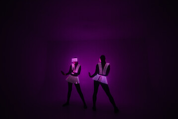 Two sexy disco dancers move in UV costumes. Parties and dances.