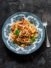 Spaghetti with mussels, squid and shrimp on a dark background, top view. Mediterranean style food
