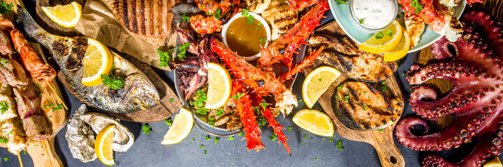 Assortment various barbecue Mediterranean grill food - fish, octopus, shrimp, crab, seafood, mussels, summer diet bbq party fest, with kebab, sauces, black concrete background, above copy space