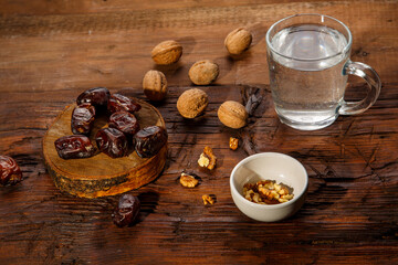 Food for iftar in holy ramadan on a wooden table dates, nuts and water.