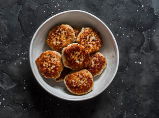 Chicken burgers cutlets in a bowl on a dark background, top view