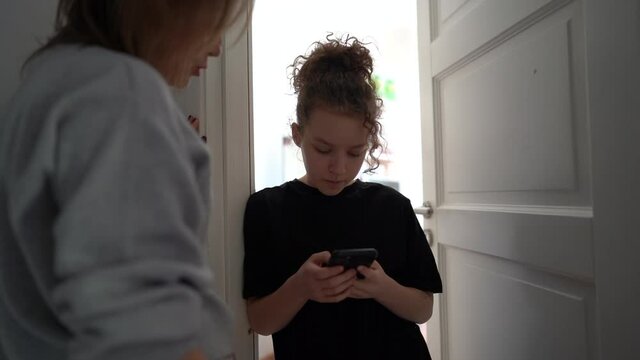 Conflict between mother and teenage daughter. The mother tries to talk to the girl. My daughter is distracted by her smartphone, Internet addiction. Teenager at her room