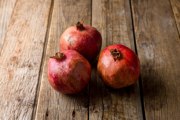 Fototapeta na wymiar three garnet on an old wooden table, pomegranate