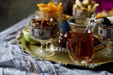 Plate with mix nuts and sweets on a eastern styled table with tea in armudu