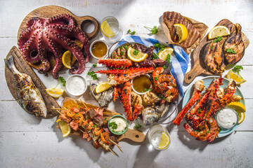 Assortment various barbecue Mediterranean grill food - fish, octopus, shrimp, crab, seafood, mussels, summer diet bbq party fest, with kebab, sauces, white wooden background, above copy space