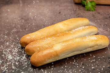 Breadsticks with sea salt being sprinkled on top