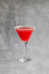 A red drink in a martini glass with a sugar or salt coated  edge