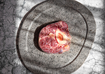 Raw ossobuco on stone gray plate, sunlight immitation