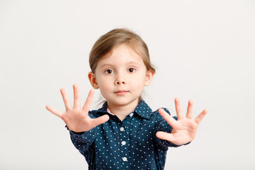 Little sweet caucasian girl 4-6 years old wearing a blue dress with polka dots stretched her palms to the camera