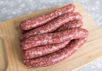Homemade raw sausages lie on a wooden board