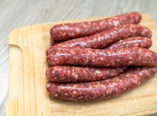 Homemade raw sausages lie on a wooden board