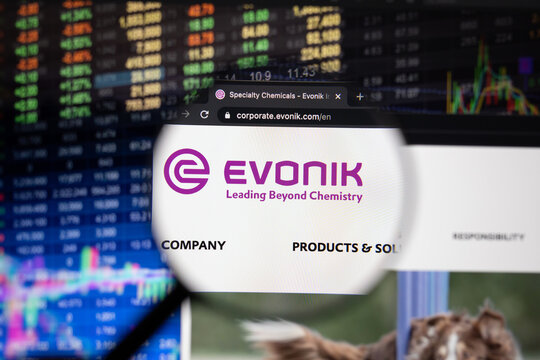 Evonik company logo on a website with blurry stock market developments in the background, seen on a computer screen through a magnifying glass