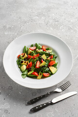 Salad with avocado, lettuce, tomato and flax seeds on gray background.Close up