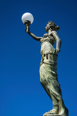 posąg kobiety, lampa miejska, statue of a woman with a lamp against the sky