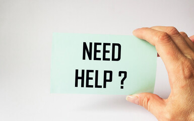 Sticker with text NEED HELP holds a female hand on a light background.