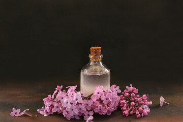 Obraz na płótnie Canvas Lilac flower and lilac oil in bottle on wooden table