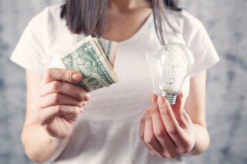 girl holding a light bulb and money