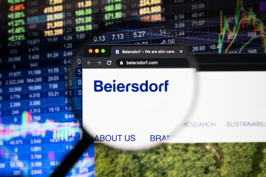 Beiersdorf company logo on a website with blurry stock market developments in the background, seen on a computer screen through a magnifying glass