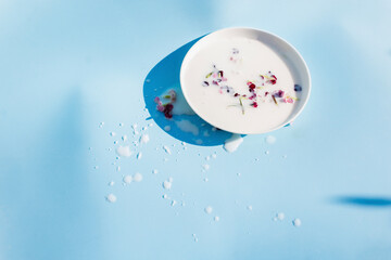 milk with flowers in a saucer on a blue background