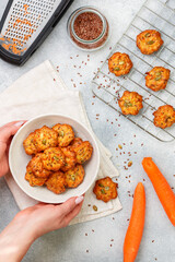 Women's hands and a white plate with freshly baked homemade carrot cookies with flax seed and pumpkin seeds. Breakfast. Delicious and healthy vegetarian snack. Selective Focus