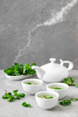 Herbal mint tea in small traditional chinese cups and fresh leaves, healthy antioxidant drink