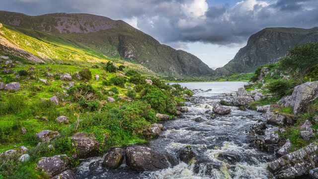 Mountain river flowing from Black Lake in Gap of Dunloe. Green hills at sunset in Black Valley, MacGillycuddys Reeks mountains, Ring of Kerry, Ireland