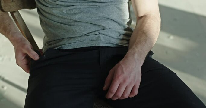 Unrecognizable man taking knife out of pocket