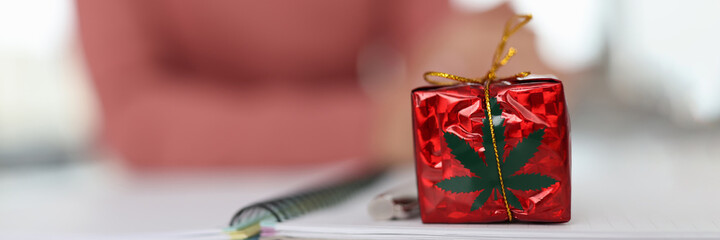 Red gift with marijuana logo on table