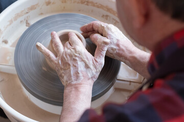 Potter wheel and hands of craftsman making a jug