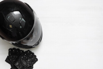 A motorcycle helmet and sport gloves on the white wooden table background with copy space.