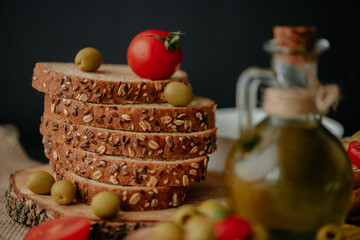 Baked sliced bread beautifully placed on a textured surface with cherry tomatoes and olives placed on and around it, nicely decorated in studio environment