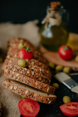 Baked sliced bread beautifully placed on a textured surface with cherry tomatoes and olives placed on and around it, nicely decorated in studio environment
