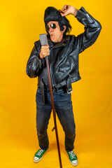 Funny portrait of mature rocker. An old singer dressed in rockabilly style in action