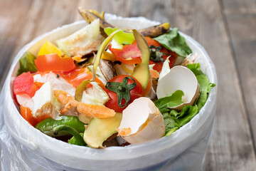 Food leftovers in compost bin on wooden background, compost, vegetable peels concept. Copy space, Sustainable and zero waste