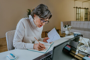 Mature woman learning foreign language using a laptop at home