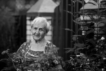 Portrait of old woman in the garden. Black and white photo.