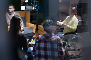 Office workers and person in a wheelchair discussing business moments in a modern office. Disability and business concept