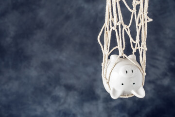 Trapped piggy bank in net on dark background with copy space. Avoid debt traps and speculation. Savings and retirement financial scams - 431395031