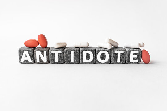 ANTIDOTE the word on stone cubes. Cubes stand on a white surface, many white and red pills. Medicine concept. medicine taken to counteract a particular poison