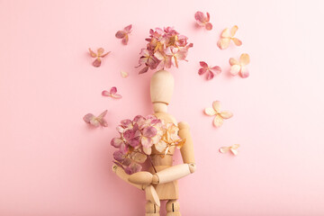 Wooden mannequin holding hydrangea flowers on pink pastel background. copy space. - Powered by Adobe