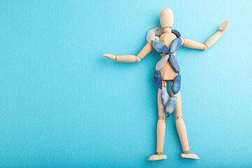 Wooden mannequin with blue agate beads on blue pastel background. copy space.