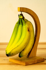 Bunch of ripe bananas hanging from stand on table