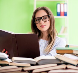 Young female student preparing for exams with many books