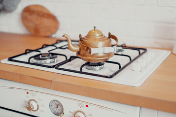 An antique item in the apartment. Copper metal retro teapot vintage stands on a gas stove. Clean...