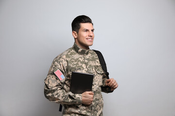 Cadet with backpack and tablet on light grey background. Military education