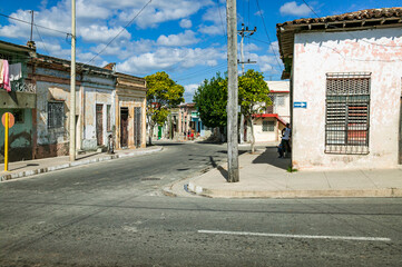 Residential street corner with flat roofed weathered stucco houses, one way street arrow, and local...