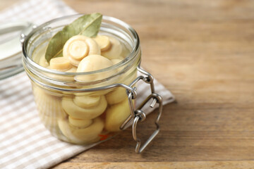 Jar with marinated mushrooms on wooden table, closeup. Space for text