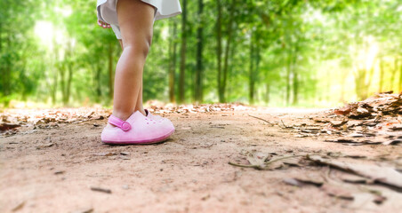 baby girl walks in a pathway with a wooded environment