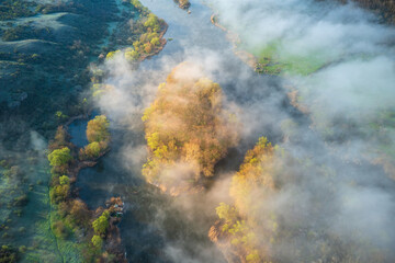 aerial view to island with trees in light between fog on the river